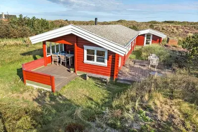 a red house with a deck in a field at 651-Snedsted-Somaerkevej-50 in Snedsted
