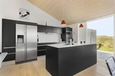 a kitchen with a stainless steel refrigerator and black cabinets at 768-Snedsted-Somaerkevej-68 in Snedsted