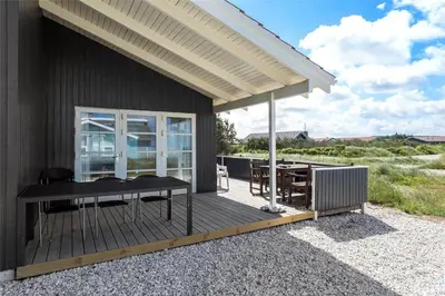 a house with a deck with a table and a grill at 975-Thisted-Klitstien-45 in Torsted