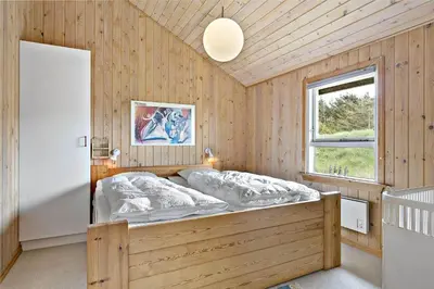 a bedroom with a large bed in a wooden wall at 675-Thisted-Tunvej-15 in Thisted