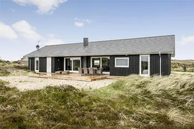 a black house with a deck on the beach at 899-Snedsted-Somaerkevej-76-B in Snedsted