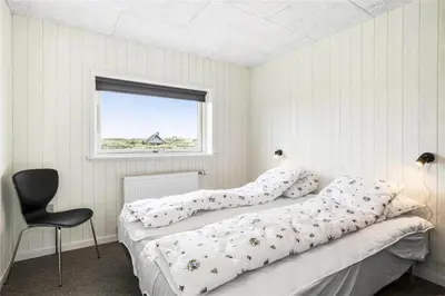 a bedroom with a bed and a chair and a window at 899-Snedsted-Somaerkevej-76-B in Snedsted