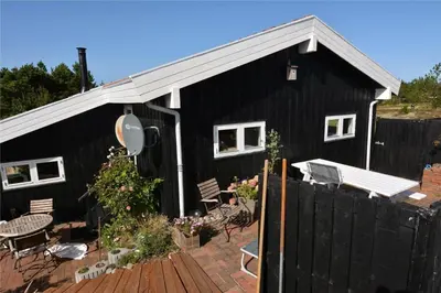 a black house with a patio and a fence at 1030-Thisted-Lyngstien-15-A in Torsted