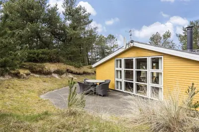 a yellow house with a table and a patio at 710-Thisted-Klitrosevej-10 in Thisted