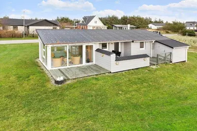 a small white house with a deck in a field at 276-Thisted-Nordsovej-76 in Thisted