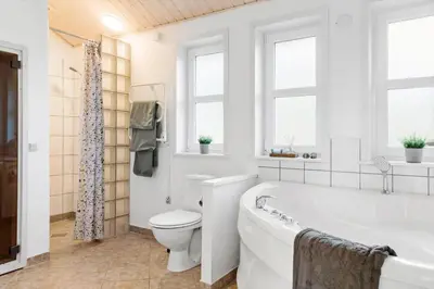 a bathroom with a tub and a toilet and windows at 1050-Thisted-Spanggardsvej-5 in Torsted