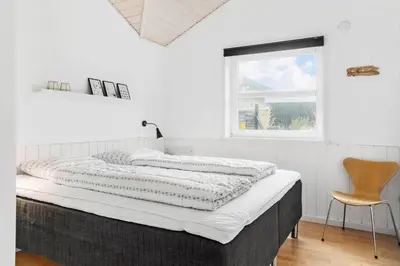 a bed in a room with a chair and a window at 1050-Thisted-Spanggardsvej-5 in Torsted
