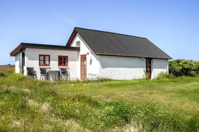 a white house with chairs in a field at 957-Thisted-Hvidbakken-33-Lille-hus in Torsted