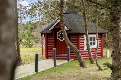 a red cabin with a black roof in the woods at 854-Thisted-Molgaardsvej-3 in Thisted