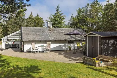 a house with a patio and a table and an umbrella at 834-Thisted-Revlingvej-9 in Thisted