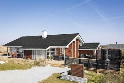a house on the beach with a fence in front of it at 951-Thisted-Bavnbak-39 in Torsted