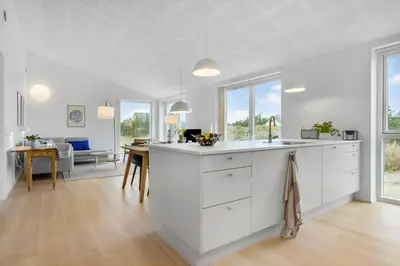 a kitchen with white cabinets and a dining room at 1305-Snedsted-Klitfogedvej-5 in Snedsted