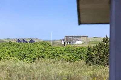 a house in a field with houses in the background at 928-Thisted-Kobbelsti-15 in Torsted