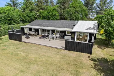 a house with a large wooden deck in a field at 153-Vestervig-Sivsangervej-4 in Vestervig