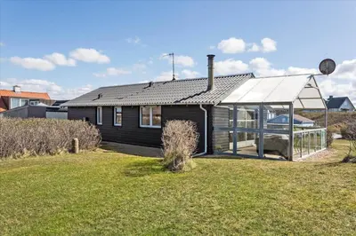 a small black house with a greenhouse in a yard at 670-Thisted-Krebsvej-4 in Thisted