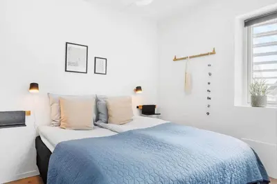a bedroom with a bed with a blue comforter and a window at 556-Thisted-Havstokken-24-A in Thisted