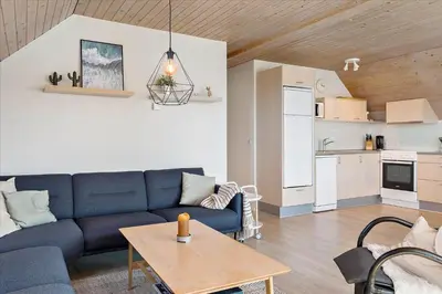 a living room with a blue couch and a kitchen at 716-Thisted-Kristinesvej-34 in Thisted