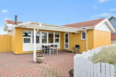 a yellow house with a table and a fence at 860-Thisted-Gronnevej-6 in Thisted