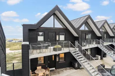 a black house with a balcony and stairs at 1316-Thisted-Havstokken-16-A in Thisted