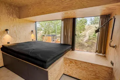 a bedroom in a tiny house with a large window at 1061-Thisted-Spanggardsvej-85-B in Torsted