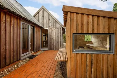 a wooden house with a bench next to it at 1061-Thisted-Spanggardsvej-85-B in Torsted