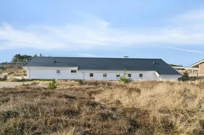 a white house with a black roof in a field at 1064-Thisted-Klitstien-25 in Torsted