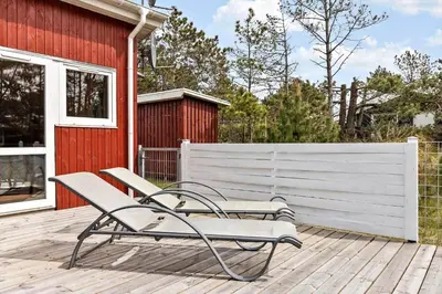 a bench sitting on a deck next to a red building at 1326-Thisted-Blabaervej-6 in Thisted