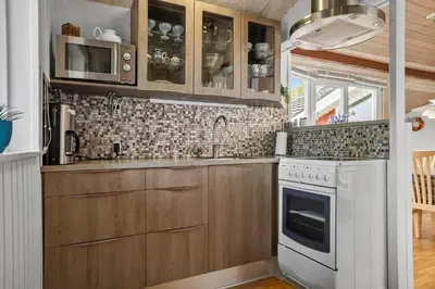 a kitchen with wooden cabinets and a white stove top oven at 1326-Thisted-Blabaervej-6 in Thisted