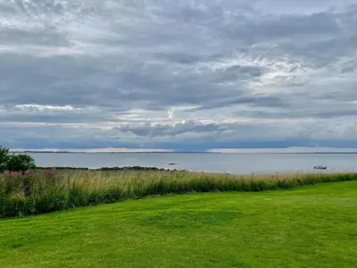 a grassy field with a view of a body of water at Holiday home for family in Denmark in Løgsted