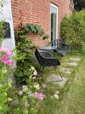 two chairs and a table in front of a brick building at Cozy property in the countryside in beautiful nature in Vinderup