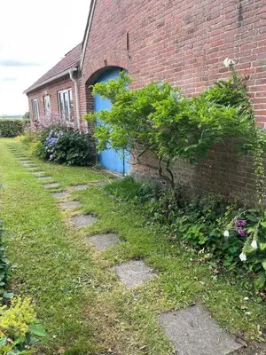 a brick building with a blue door and a yard at Cozy property in the countryside in beautiful nature in Vinderup