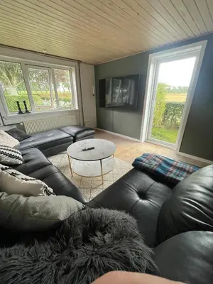 a living room with a leather couch and a table at Cozy property in the countryside in beautiful nature in Vinderup