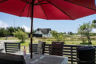 a wooden table with a red umbrella on a deck at 1353-Snedsted-Ebenezervej-24 in Snedsted