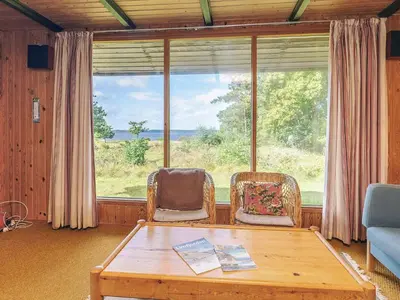 a living room with a table and chairs and a large window at 8 person holiday home in Skals-By Traum in Skals