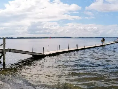 two people walking on a dock in the water at 4 star holiday home in Farsø-By Traum in Farsø