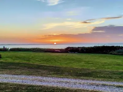 a sunset over a field with the sun in the sky at 4 star holiday home in Farsø-By Traum in Farsø