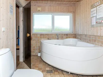 a large white tub in a bathroom with a window at 12 person holiday home in Pandrup-By Traum in Pandrup