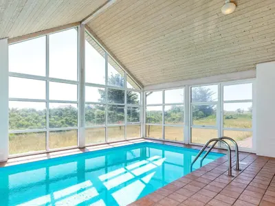 an indoor swimming pool with windows in a house at 12 person holiday home in Pandrup-By Traum in Pandrup