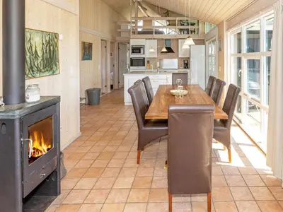 a kitchen with a dining table and a fireplace at 12 person holiday home in Pandrup-By Traum in Pandrup