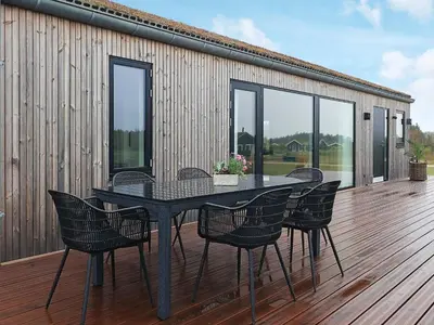 a black table and chairs on a wooden deck at 8 person holiday home in Saltum-By Traum in Saltum