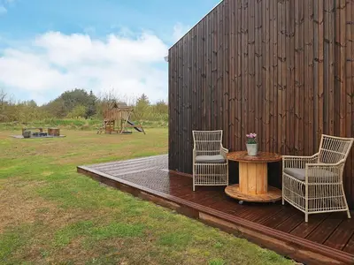 two chairs and a table on a wooden deck at 8 person holiday home in Saltum-By Traum in Saltum