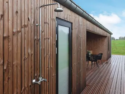 a wooden building with a door and a table on a deck at 8 person holiday home in Saltum-By Traum in Saltum