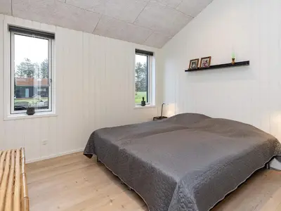 a bedroom with a large bed and two windows at 8 person holiday home in Saltum-By Traum in Saltum