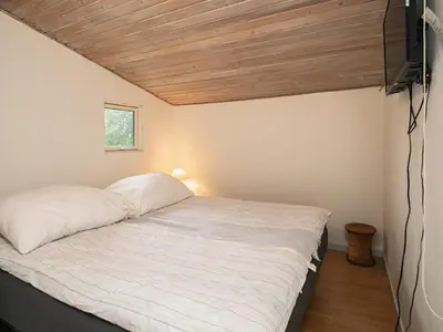 a bed in a room with a wooden ceiling at 5 person holiday home in Thyholm-By Traum in Thyholm