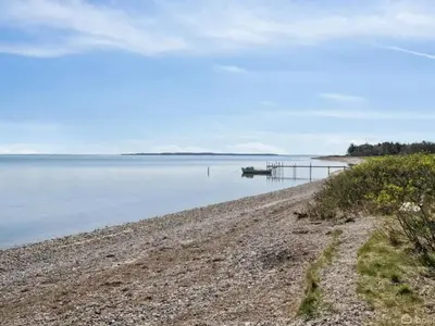 a beach with a pier and a boat in the water at 5 person holiday home in Thyholm-By Traum in Thyholm