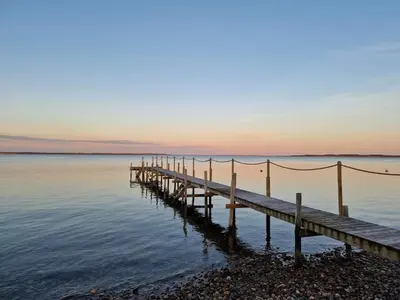 a wooden dock in the water at sunset at 8 person holiday home in Thyholm-By Traum in Thyholm