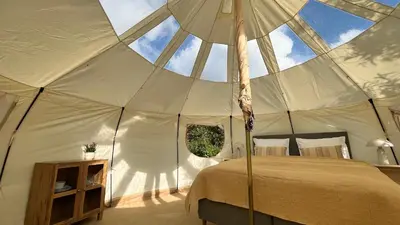 a bedroom in a tent with a bed and an umbrella at Agger Glamping - Havtornen in Vestervig