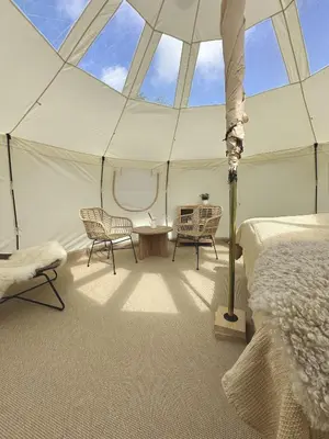 a bedroom with a tent with a bed and two chairs at Agger Glamping - Havtornen in Vestervig
