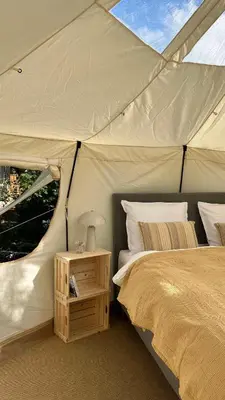 a bedroom with a tent with a bed and a night stand at Agger Glamping - Havtornen in Vestervig