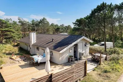 a small white house with a deck and a table at 1333-Thisted-Sandtornvej-43 in Thisted